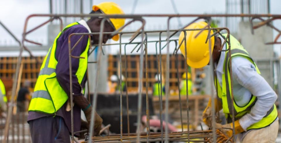 Two construction professionals in high-visibility PPE working with steel reinforcement.