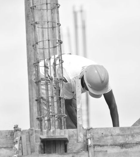 Construction professional in a hard hat working beside reinforced concrete columns.