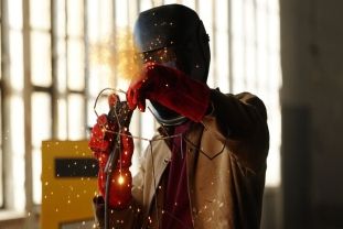 Fabricator wearing face and hand protection during active metalwork.