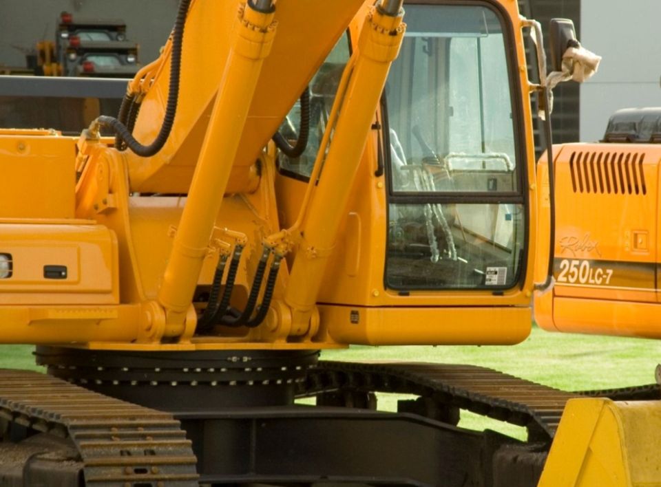 Yellow tracked excavator at an industrial equipment yard.