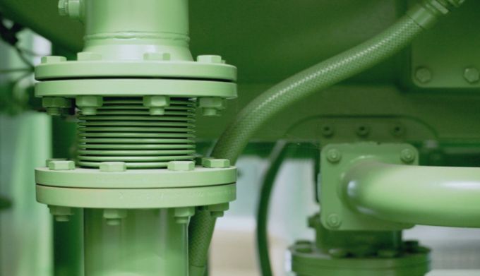 Close view of industrial pipework, flanges and flexible connections.